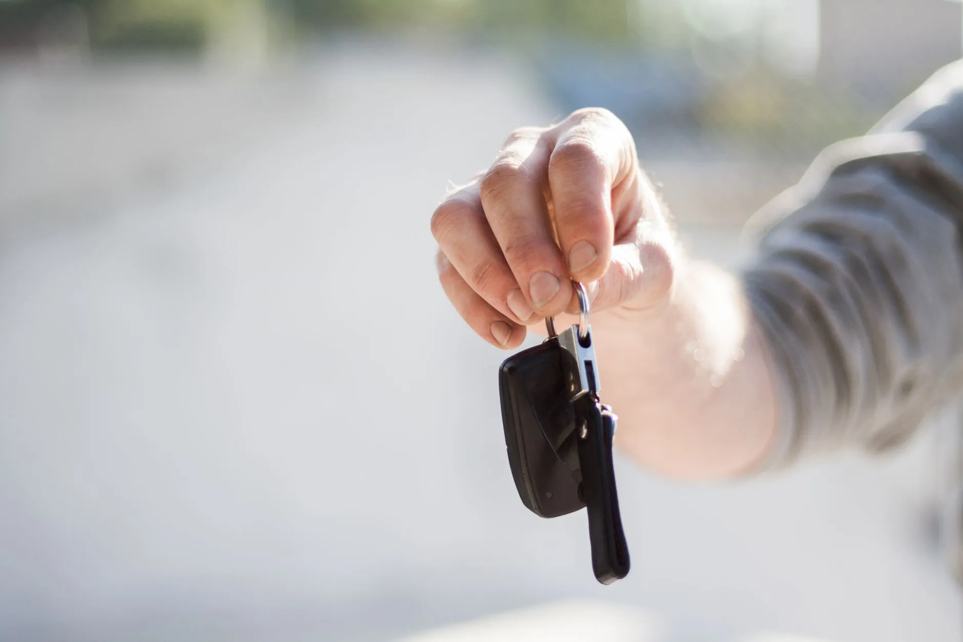 Mão estendendo a chave de um carro para o novo dono